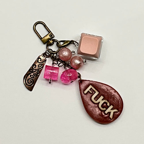 handmade Sassy Click Charm for purse or planner, with a tactile light pink clicking keyboard key, a bold resin tear drop shaped word charm, and various pink and gold beads and antique bronze hardware
