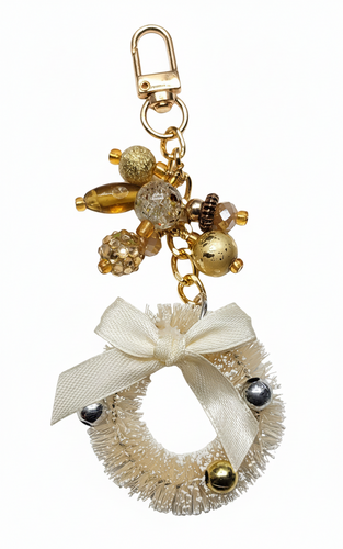 Frosty Cabin Wreath purse charm by Bougie Girl Boutique, featuring a creamy white brush-style wreath with a bow, accented by gold and silver baubles and a cluster of warm golden-toned beads.