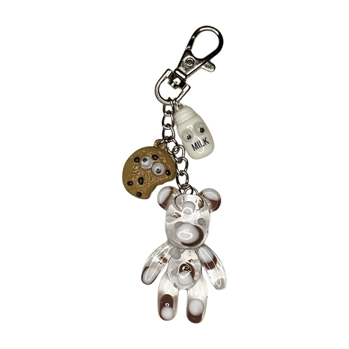 A purse charm featuring a swirled brown and white teddy bear, a small chocolate chip cookie with a bite taken out, and a tiny milk bottle, all with cute expressive faces. The charms dangle from a silver chain with a lobster clasp, making it easy to attach to bags, purses, or planners.