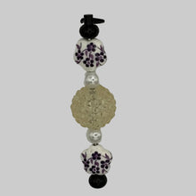 Load image into Gallery viewer, Handmade "Midnight Botanica" black Luxe Pillar purse charm featuring purple vine floral beads and a transparent faceted crystal focal, high-contrast black metal hardware.