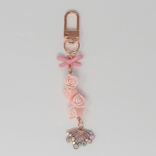 Whispering Roses charm by Bougie Girl Boutique, featuring a cluster of blush pink roses with a delicate pink bow and a stylized blossom with rhinestones.